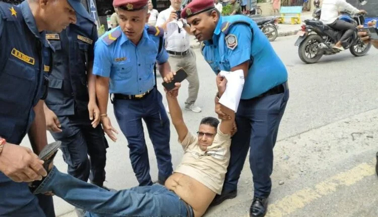 प्रदर्शन करते पत्रकार को घसीटकर ले जाते नेपाल पुलिस के जवान।